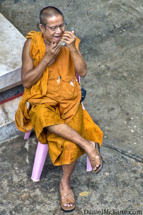 buddhist monk in vientiane doing some grooming